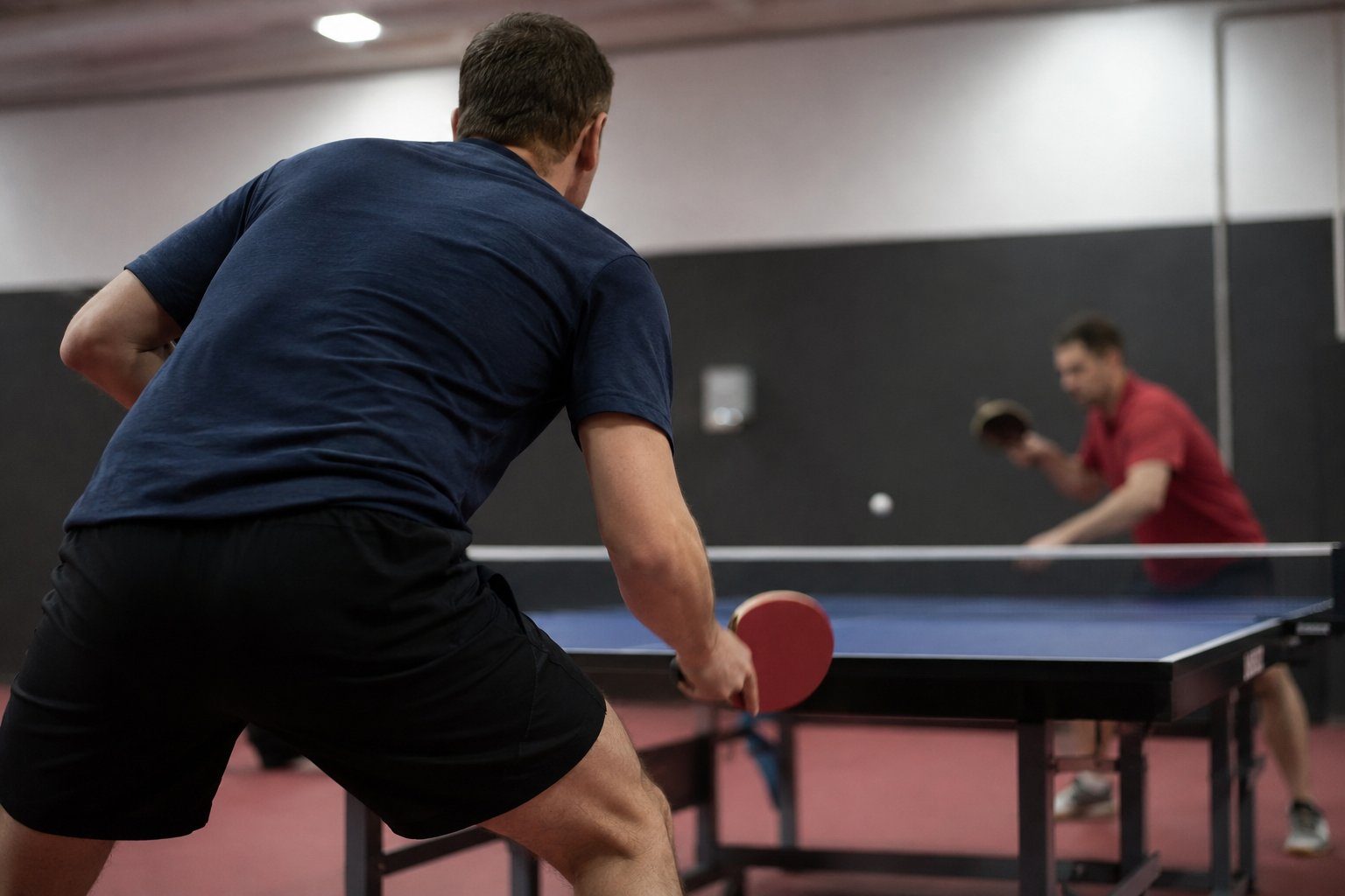 Dois jogadores em pleno jogo numa mesa de ténis de mesa