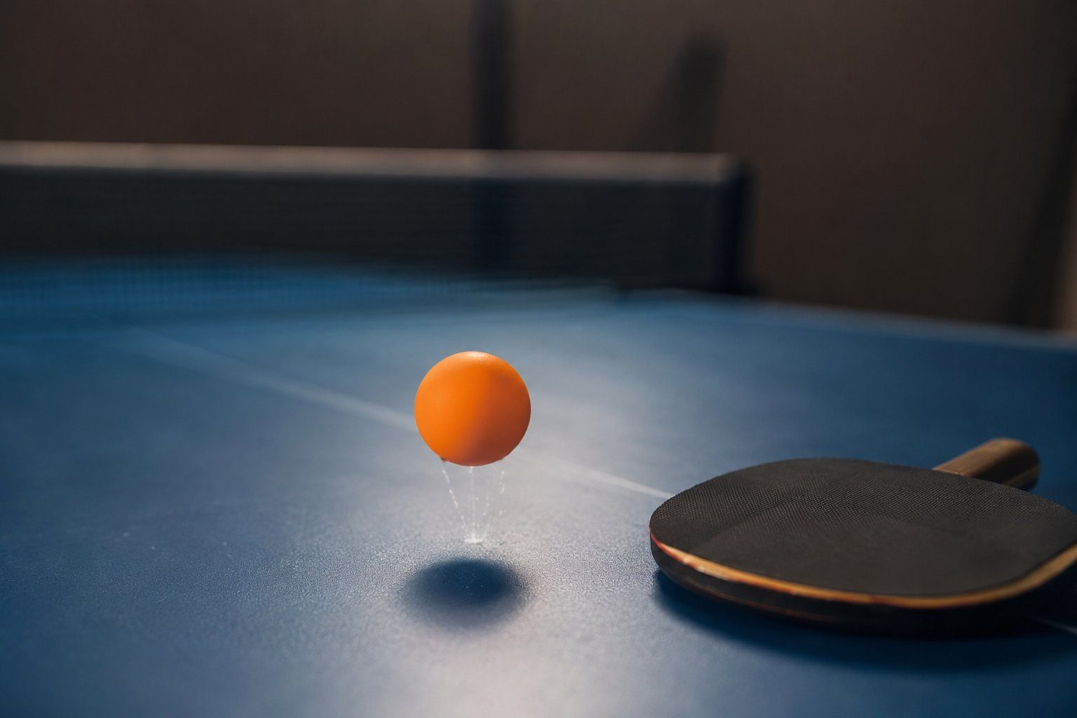 Bola de ténis de mesa em movimento sobre a mesa, junto a uma raquete
